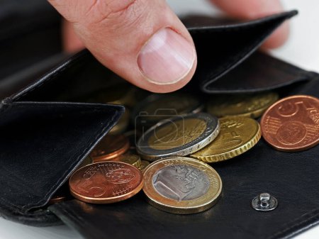 Male hand checking black leather wallet with euro coins, close-up of a open purse with loose change.