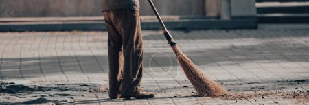 Janitor sweeping dirt on the street during the da