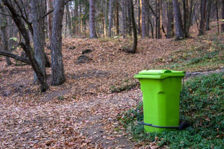 Gran bote de basura verde en el bosque, concepto de protección del medio ambiente
