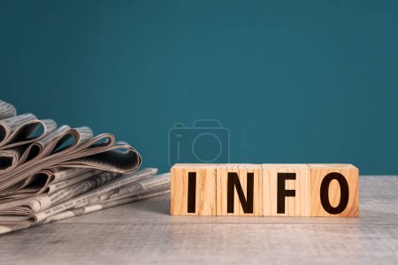 Newspapers and wooden cubes with "INFO" written on them, studio background, stock photo