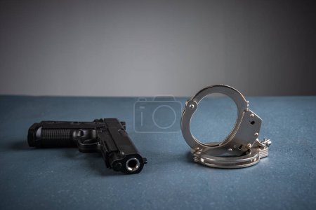 Gun and handcuffs on blue background, stock photo, criminal concept