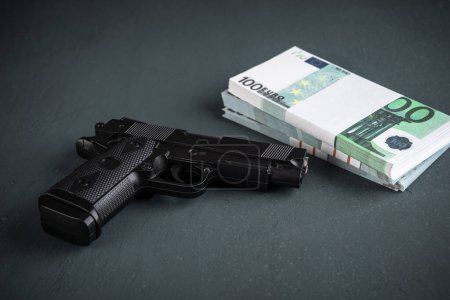 Téléchargez les photos : Pistolet et argent sur fond noir, photo de stock, concept criminel - en image libre de droit