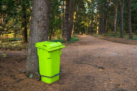 Bright green trash can in the forest, ecological concept, stock photo