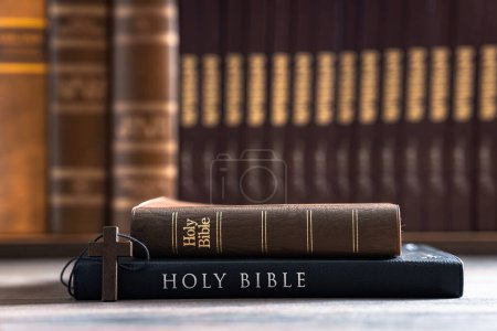 Collar de cruz de madera junto a las viejas y nuevas Biblias apiladas una encima de la otra, concepto cristiano, símbolo religioso