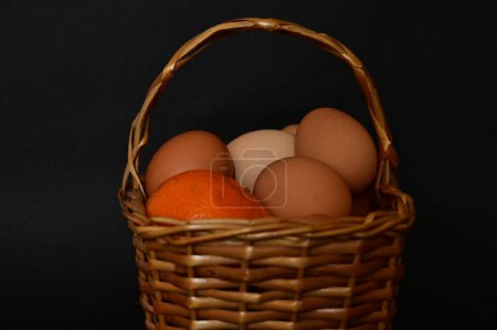 Foto de Fiesta de Pascua, huevos, frutas en canasta sobre fondo negro - Imagen libre de derechos