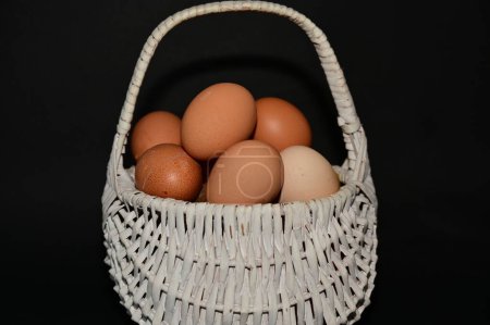 Téléchargez les photos : Panier de vacances de Pâques avec des œufs sur fond noir - en image libre de droit