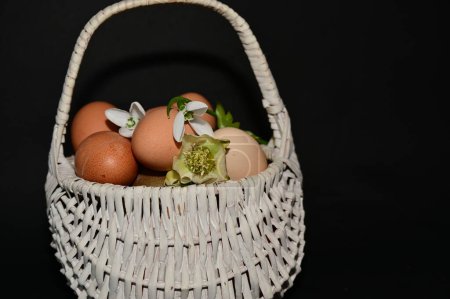 Foto de Easter holiday basket with eggs and flowers on black background - Imagen libre de derechos