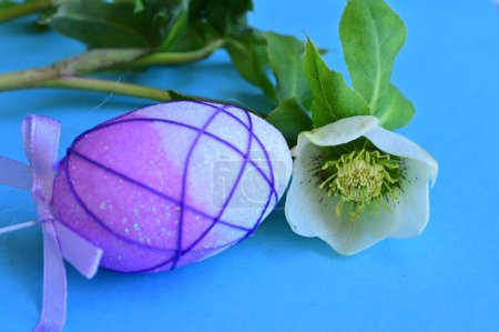 Foto de Hermosa flor y huevo de Pascua sobre fondo azul - Imagen libre de derechos