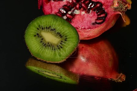 Photo for Pomegranate, kiwi fresh ripe fruits on a black background - Royalty Free Image