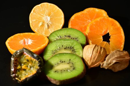 Foto de Kiwi en rodajas y naranjas, fruta de la pasión con un fondo negro - Imagen libre de derechos