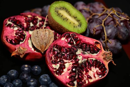 Photo for Fresh fruit with red pomegranate and kiwi on a black table - Royalty Free Image