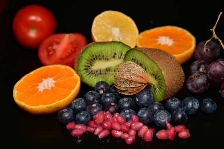 Téléchargez les photos : Fruits frais et tomates sur fond noir - en image libre de droit