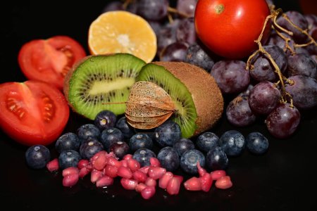 Téléchargez les photos : Fruits frais et tomates sur fond noir - en image libre de droit