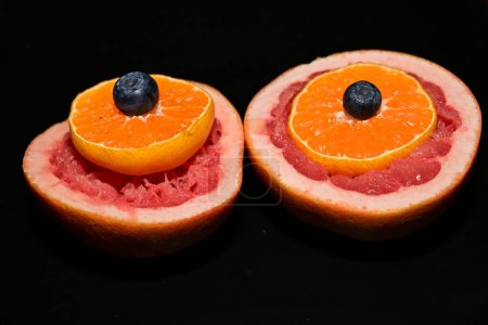 Foto de Pomelo rojo fresco con rodajas de naranja y arándanos sobre fondo oscuro - Imagen libre de derechos