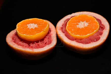 Téléchargez les photos : Pamplemousse coupé aux oranges sur fond noir - en image libre de droit