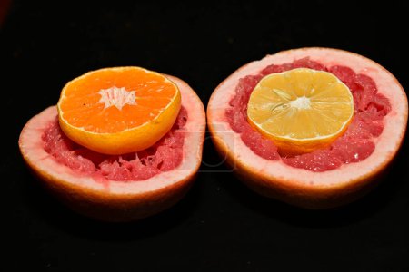 Téléchargez les photos : Pamplemousse rouge frais avec des tranches d'orange et de citron sur fond sombre - en image libre de droit