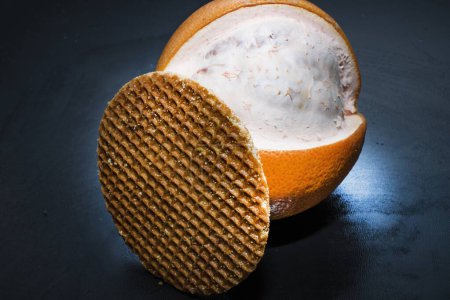 Téléchargez les photos : Un plan vertical d'une délicieuse crème glacée fraîche dans un bol avec une tranche d'orange sur fond noir - en image libre de droit