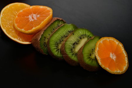 Téléchargez les photos : Tranches d'orange et de kiwi sur fond noir - en image libre de droit