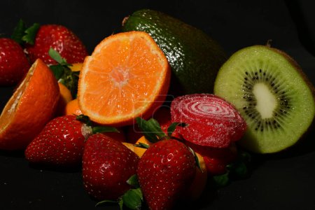 Foto de Grupo de frutas con gelatina enrollada sobre un fondo negro - Imagen libre de derechos