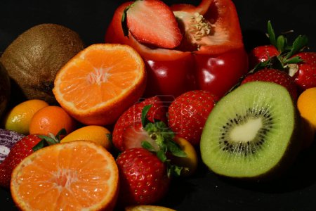 Téléchargez les photos : Assortiment de fruits et légumes avec gelée roulée sur fond noir - en image libre de droit