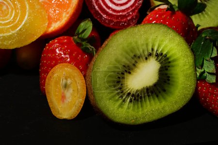 Téléchargez les photos : Assortiment de fruits et légumes avec gelées roulées sur fond noir - en image libre de droit