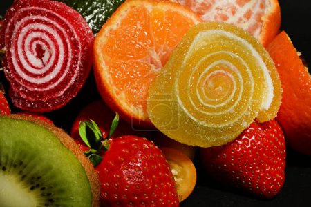 Téléchargez les photos : Assortiment de fruits et légumes avec gelées roulées sur fond noir - en image libre de droit