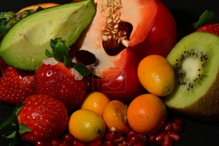 Foto de Grupo de frutas y verduras con gelatina enrollada sobre un fondo negro - Imagen libre de derechos