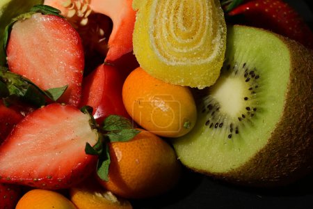 Téléchargez les photos : Groupe de fruits et légumes avec gelée roulée sur fond noir - en image libre de droit
