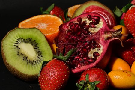 Foto de Grupo de frutas con gelatina enrollada sobre un fondo negro - Imagen libre de derechos