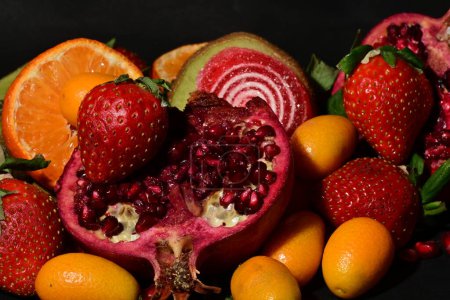 Téléchargez les photos : Groupe de fruits avec gelée roulée sur fond noir - en image libre de droit