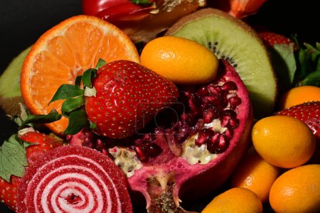 Foto de Grupo de frutas y verduras con gelatina enrollada sobre un fondo negro - Imagen libre de derechos