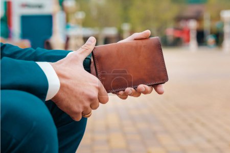 Photo for Man in an elegant blue suit holding a brown handmade leather document holder. Close-up of the hands. The concept of style and fashion. - Royalty Free Image