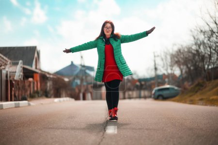 Photo for A senior caucasian beautiful woman walks along the road, keeping her balance on the central marking. The concept of psychology. - Royalty Free Image