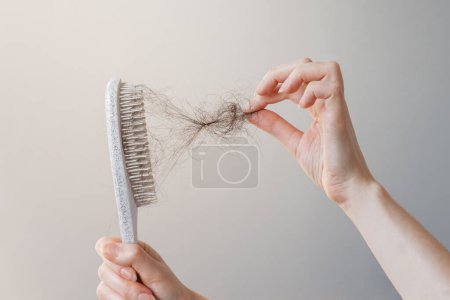 Téléchargez les photos : Female hand pulls out a clump of hair from a comb. Close-up. The concept of alopecia and hair loss. - en image libre de droit