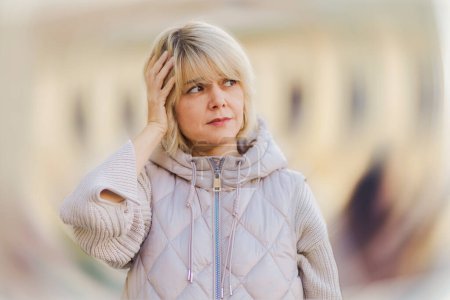 Photo for Psychology and mental health. Portrait of Caucasian adult woman holding at her head. Defocused twisted background. Concept of dizziness, headache and frustration. - Royalty Free Image