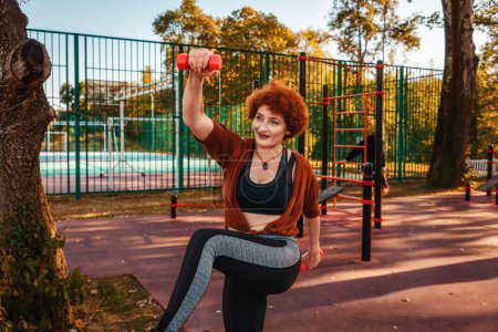 Photo for Fitness and aerobic at city park. Mid adult happy Caucasian ginger hair woman is doing sports. Concept of healthy lifestyle. - Royalty Free Image