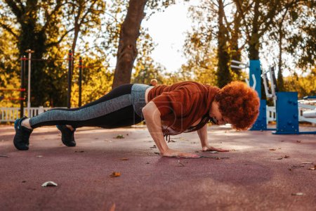 Photo for Low angle view of Caucasian adult woman does push-ups from the floor. Copy space. Healthy lifestyle concept. - Royalty Free Image