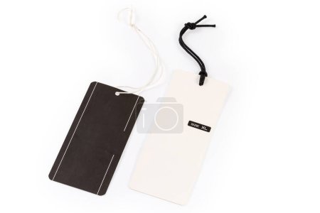 Blank clothing swing tag in the form of the white carton sheet with clothing size designation on a black rope and black swing tag on a white rope on a light background