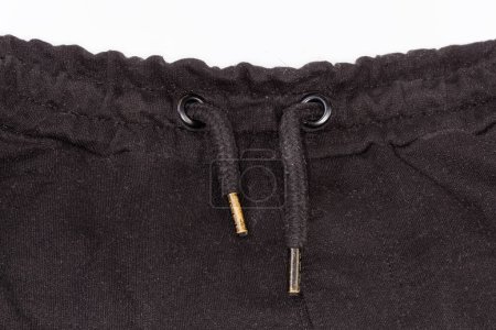 Photo for Fragment of the black knitted pants waist with drawstring with metal aglets inserted through the holes reinforce with eyelets - Royalty Free Image