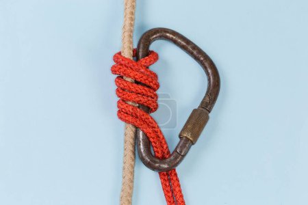 Téléchargez les photos : Rope Bachmann knot tied with accessory cord using steel carabiner on the main rope on a blue background - en image libre de droit