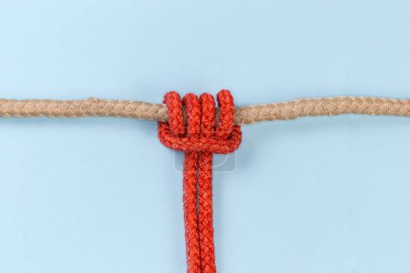 Téléchargez les photos : Rope Prusik knot tied with an accessory cord on the main rope on a blue background - en image libre de droit