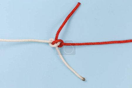 Foto de Tightened rope Hunter's knot used  to join of two ropes, view on a blue background - Imagen libre de derechos