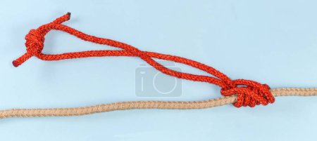 Foto de Rope klemheist knot tied with a loop from the accessory cord on the main rope on a blue background - Imagen libre de derechos