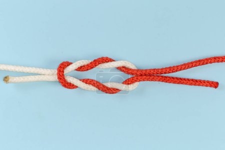 Téléchargez les photos : Not tightened rope double reef knot, modification of the surgeon's knot containing two each double overhand knots in the bottom and on the top on a blue background - en image libre de droit