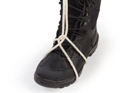 Foto de Rope knot Clove hitch tied around the black hiking boot as loops for the leg used for lifting in the technique of "chest-leg" in climbing on a white background - Imagen libre de derechos