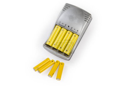 Foto de Rechargeable batteries AA size inserted in battery charger and alkaline batteries AAA size on a white background - Imagen libre de derechos