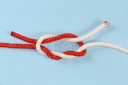 Téléchargez les photos : Not tightened rope Surgeon's knot tied with an accessory cord, view on a blue background - en image libre de droit
