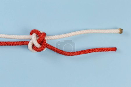Foto de Tightened rope Diamond knot, also known as Knife lanyard knot on a blue background - Imagen libre de derechos