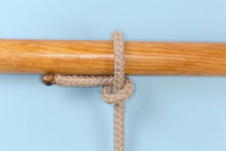 Seilknoten Halbe Anhängerkupplung um eine Holzstange gebunden, Nahaufnahme auf blauem Hintergrund