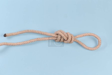 Foto de Nudo de cuerda Figura-nueve lazo, también conocido como nudo intermedio atado con cuerda trepadora, vista sobre un fondo azul - Imagen libre de derechos